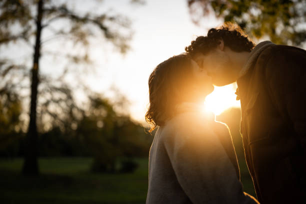 couple in park - silhouette kissing park sunset imagens e fotografias de stock