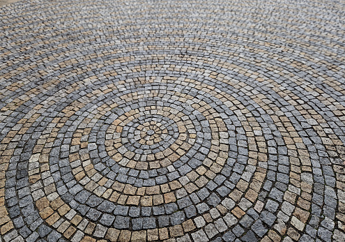 stone paving in the square folded into circles with a larger tile in the middle of the gray granite paving. the circles on the water are symbolic of the paving, the big and the small blend together, encircle, encircled,