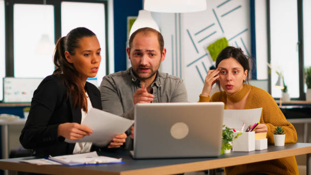 istock Colleagues sitting at desk, working with laptop computer, showing first project results 1864190484