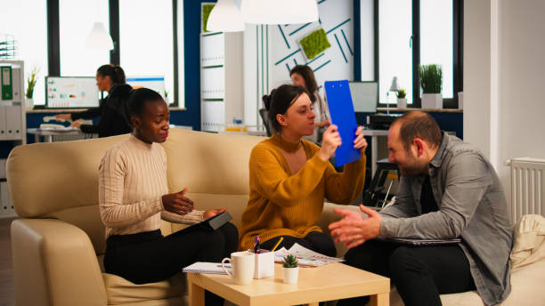 Angry manager screaming at diverse employees hitting man with clipboard in head