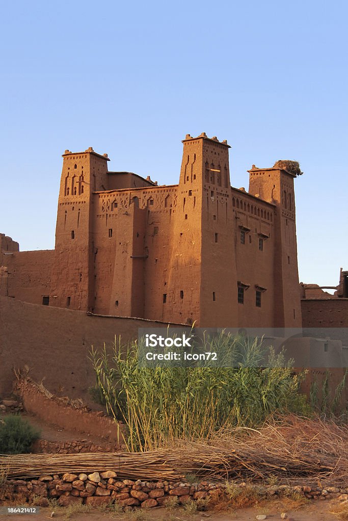 Marrocos: Pôr do sol na antiga Aït argila kasbah de Benhaddou - Foto de stock de Ponto Turístico royalty-free
