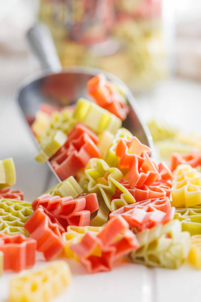 istock Uncooked raw pasta. Various Christmas shapes. Pasta in scoop on white table. 1864217848