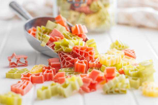 istock Uncooked raw pasta. Various Christmas shapes. Pasta in scoop on white table. 1864217851