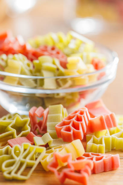 istock Uncooked raw pasta. Various Christmas shapes. Pasta on wooden table. 1864219605