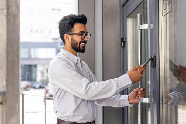 istock Young businessman using phone to open office door of building, man happy using wireless access, businessman going to work happy smiling 1864219635