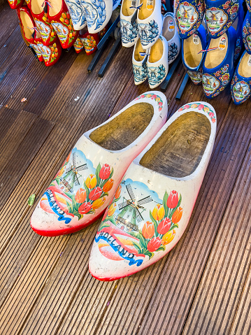 Amsterdam, Holland, 12.12.2022: Traditional souvenir clogs for sale, a must from the Netherlands. Colourful wooden clogs painted with regional motifs. Travel destination background of Dutch tradition.