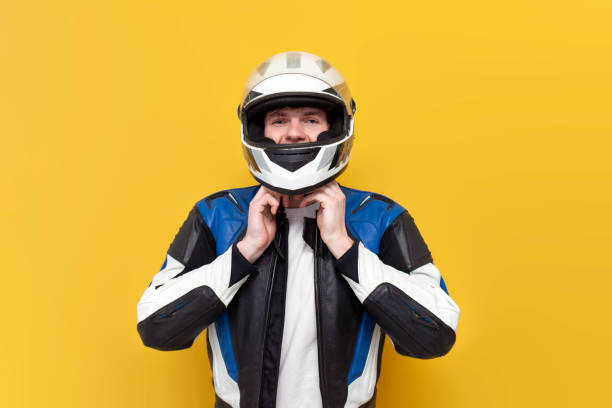 istock young guy motorcyclist in leather jacket puts on helmet on yellow isolated background 1864223036