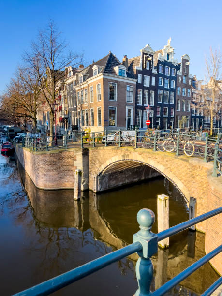 Beautiful cityscape of Amsterdam. Typical Dutch houses and a bridge with bicycles over a canal. Old brick houses from the 17th and 18th century along a canal on a sunny winter day. Travel destination and transport background, copy space.