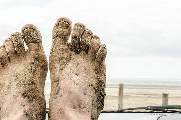 Man feet in sandals covered in mud