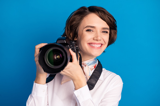 Portrait of charming cheerful person toothy smile hands hold photo camera isolated on yellow color background