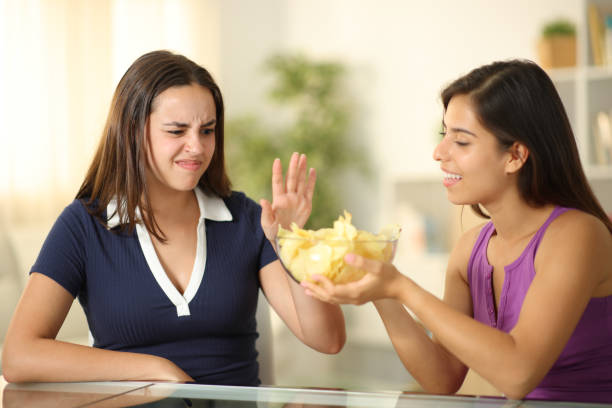 istock Woman offering potato chips to a friend who refuses it 1864240021