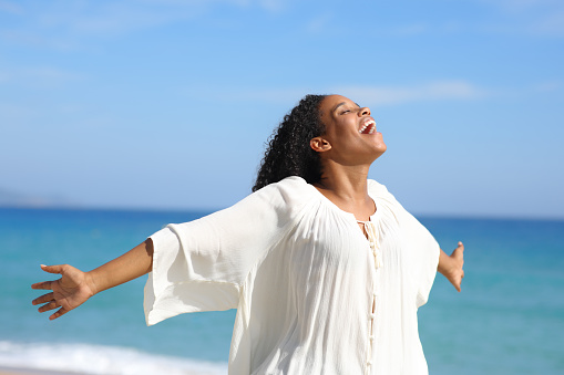 Black woman screaming and outstretching arms on the beach