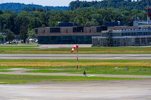 Red and white striped windsock waving at Zürich Kloten Airport on a sunny summer day. Photo taken July 23rd, 2023, Kloten, Canton Zürich, Switzerland.