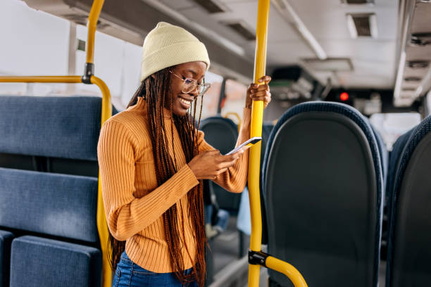 istock Smiling beautiful young woman using phone while riding in a bus 1864271811