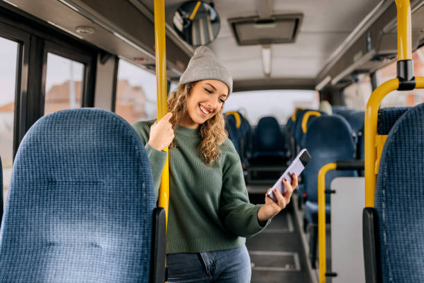 young smiling casually clothed woman using smart phone while riding in a public bus - bus riding public transportation businessman imagens e fotografias de stock