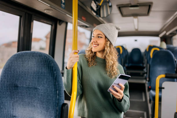 istock Young smiling casually clothed woman using smart phone while riding in a public bus 1864272324