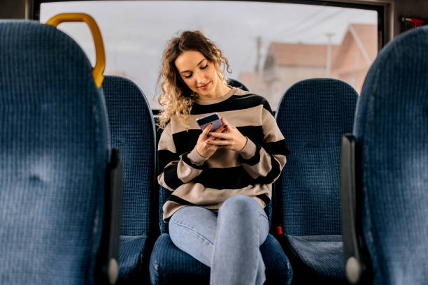 young beautiful woman using smart phone while riding in a bus - bus riding public transportation businessman imagens e fotografias de stock