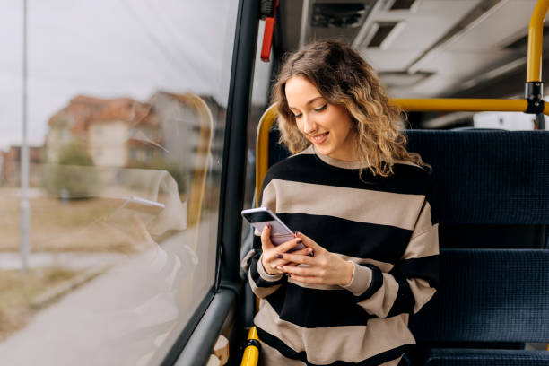 young beautiful woman using smart phone while riding in a bus - bus riding public transportation businessman imagens e fotografias de stock