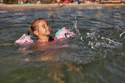 Beautiful girl enjoying sea on a beautiful sunny day. She is happy, smiling, enjoying and laughing.