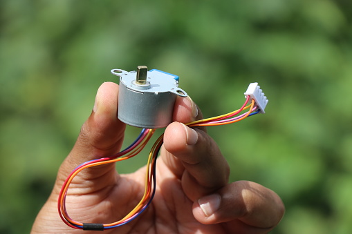 Stepper motor that runs on a dc power isolated on nature background held in hand