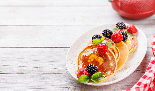 Tasty homemade pancakes with berries and honey syrup. With copy space