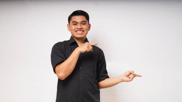 istock Young Asian man smiling when looking and pointing to the left side on white background. studio shot 1864315376