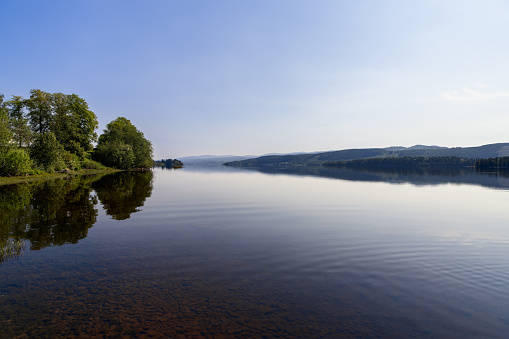 Tranquil waters of Snasavatnet, Norway's sixth-largest lake, mirror the dense forests lining its shores, nestled in Steinkjer and Snasa's serene landscape