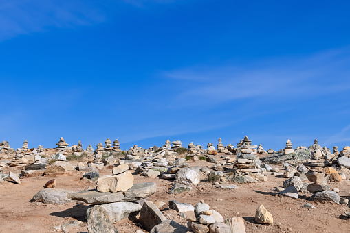 Hand-crafted stone pyramids by visitors near the Arctic Circle Center in Rana, Nordland, Norway, captured in a summer setting under a clear blue sky