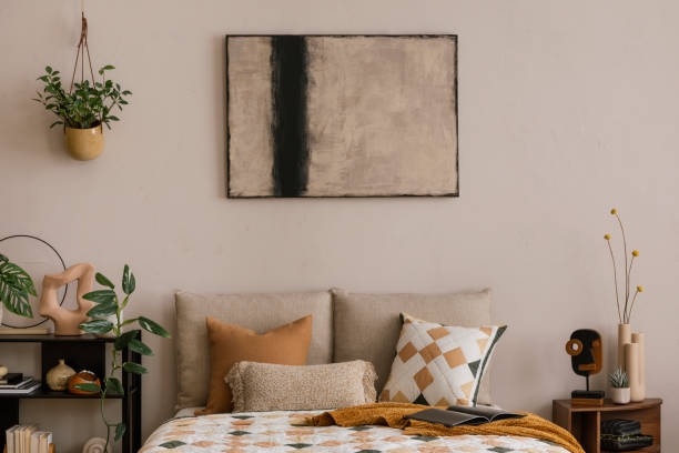 istock Creative composition of bedroom interior with bed, beige and orange bedding, plaid, patterned rug, red armchair, black rack, wooden bedside table and personal accessories. Home decor. Template. 1864331828