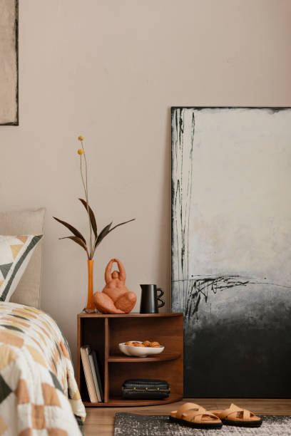 istock Creative composition of bedroom interior with mock up poster frame, bed, beige and orange bedding, patterned rug, wooden bedside table and personal accessories. Home decor. Template. 1864332361