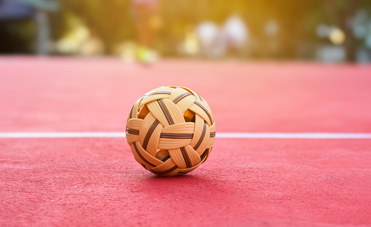 Sepak takraw ball on red floor of outdoor court, blurred background, recreactional activity and outdoor sports in Southeast asian countries concept.