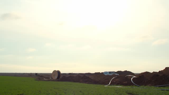 Big cable spool in the field with cables coming out of the trenches, 4k