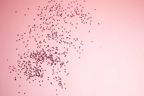 istock Greeting background with empty space. Violet sparkle sequins, glitter in heart shape on a gentle pink background 1864376156