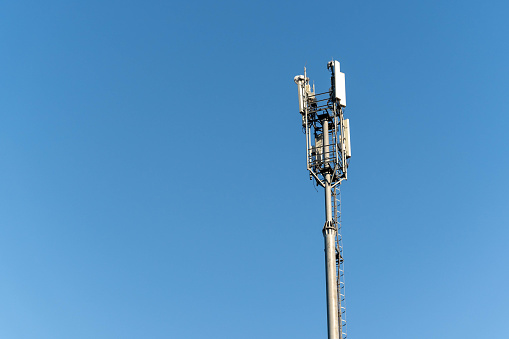A telecommunications tower, also known as a cell tower, is standing tall and prominent against a vibrant blue sky, representing modern technology and communication infrastructure.