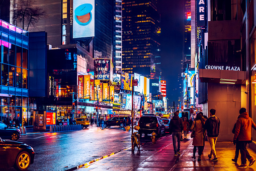 New York, USA - February 6, 2020: City life at rainy nighttime. Beautiful cityscape. Outdoors advertising with famous brands. Crowne Plaza and Olive Garden. Tourist destination, entertainment center.
