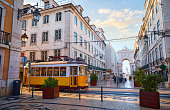 Lisbon, Portugal. Yellow touristic retro tram. Triumphal Arch of