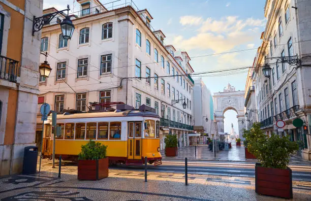 Photo of Lisbon, Portugal. Yellow touristic retro tram. Triumphal Arch of