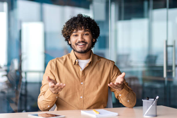 istock Webcam view, online video call, man smiling talking and gesturing looking at camera satisfied, businessman inside office at workplace, talking with colleagues 1864418006