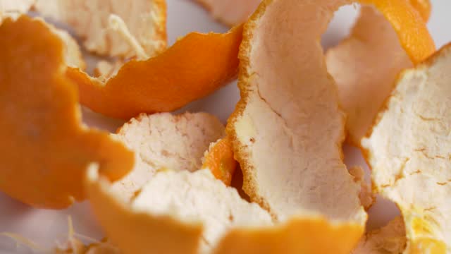Fresh orange fruit peels on a white ceramics close up. Rotation