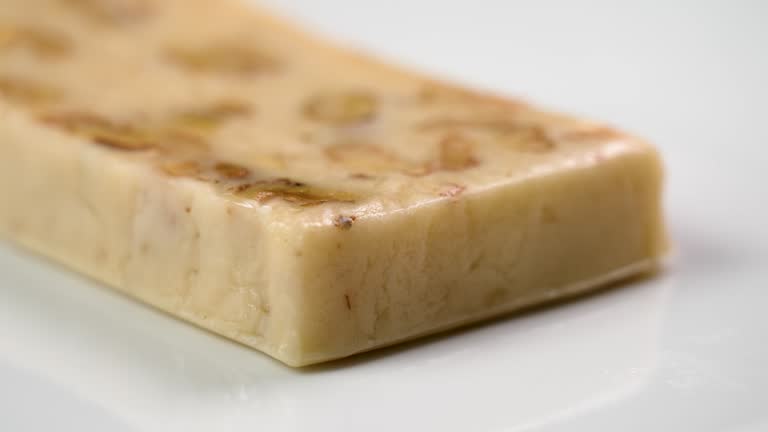 Traditional Spanish Christmas Turron with almond and nougat on a white ceramic dish close up. Rotation