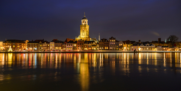 Nighttime view on the city of Deventer located at the banks of the river IJssel in Overijssel, The Netherlands in the dark december days before Christmas. The tower of the St. Lebuinus Church or great Church is a landmark in the city center.