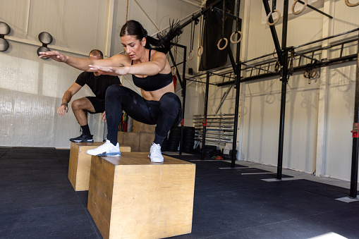 Two professional woman athlete doing plyometric training in the Fitness group lifting dumbbell in the industrial gym