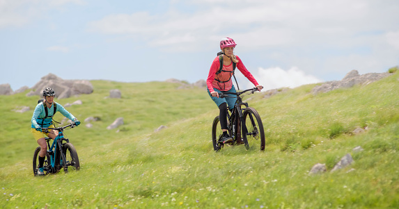 Mature women riding  electric bicycle in meadow.