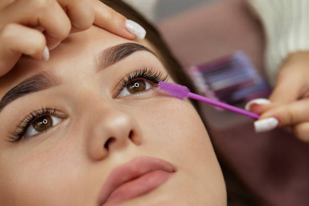 istock master combs eyelashes of client after eyelash extension procedure 1864523715