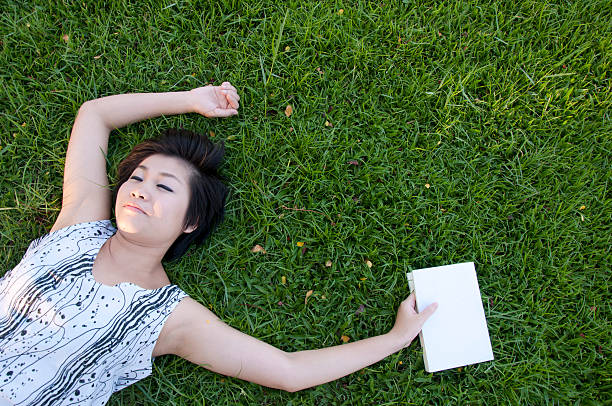 istock Young woman reading a book in the field 186452473