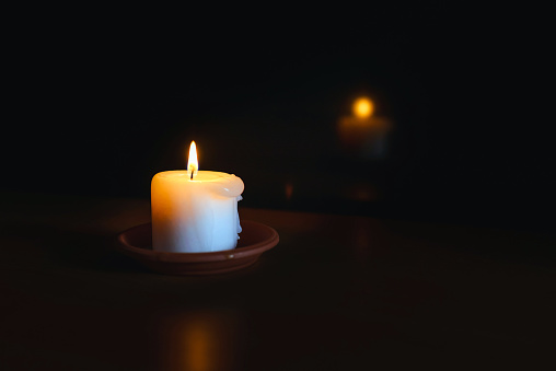 A burning candle.Bright light on dark background.RIP darkness template. lighting a candle in the darkness.the reflection of the candle in the dark mirror.