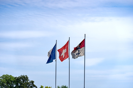 Three flags with Swiss flag and flagpoles at City of Zürich waving on a sunny summer day. Photo taken July 23rd, 2023, Zurich, Switzerland.