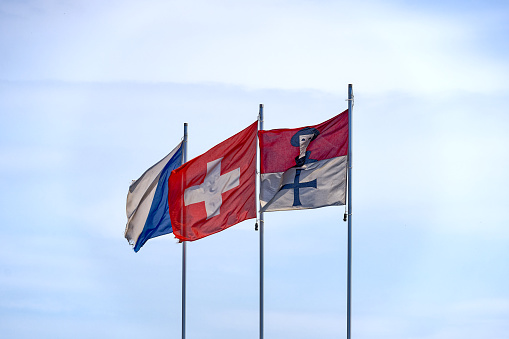 Three flags with Swiss flag and flagpoles at City of Zürich waving on a sunny summer day. Photo taken July 23rd, 2023, Zurich, Switzerland.