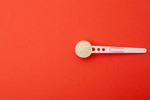 Spoon with wheat dairy-free porridge on a red background. The concept of feeding babies with gluten-free healthy porridge for the first time. Copy space for text, monocomponent