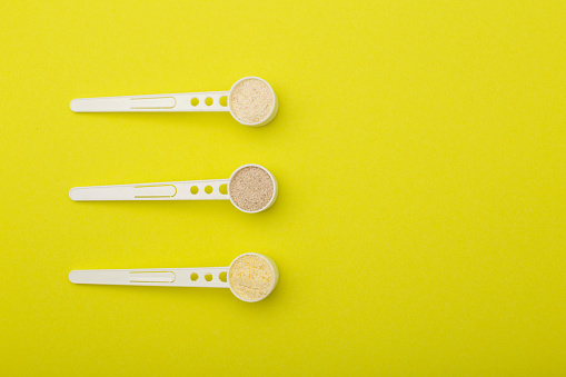 A set of spoons with different buckwheat, rice and wheat porridges on a yellow background. Dairy-free cereals with vitamins and minerals for children's first complementary feeding. Copy space for text